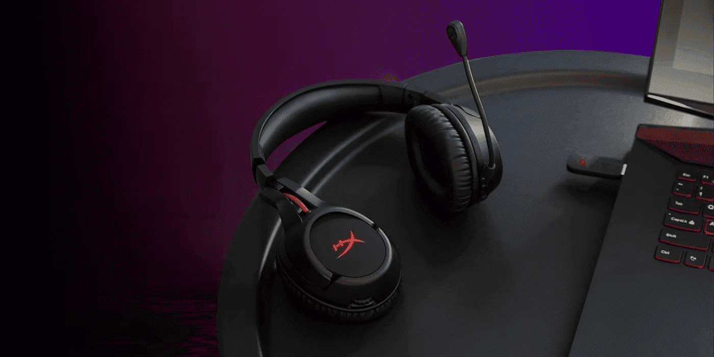 Black HyperX gaming headset with microphone and red logo resting on a dark desk with purple ambient lighting