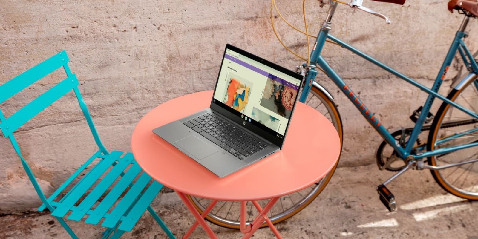 HP Chromebook on a round pink table outdoors, next to a turquoise chair and a vintage blue bicycle